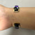 An image of the back view of the Black Jade Fire Opal Raoul Sosa women's bracelet with diamonds on a model's hand showing the open back cuff style bracelet in 14K yellow gold.