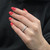 An image of a Rachel Koen diamond ring worn on the ring finger of a woman's left hand, which is elegantly positioned against a black background. The hand is angled slightly to the right with the palm facing down, giving a clear view of the ring's top and its encrusted diamonds. The photo is taken from a close, yet comfortable distance, emphasizing the ring's intricate design and the shiny red nail polish on the fingers.The ring is pre-owned in a great condition. 