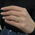 An image of a Rachel Koen brand women's ring with diamonds, worn on the ring finger of a woman's left hand. The ring features multiple sparkling diamonds set in a yellow gold band, presented at a close distance and a slight angle to show the ring's profile and the stones' brilliance. The person's hand is resting against a dark background, emphasizing the jewelry.The ring is pre owned in a great condition. 