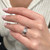 An image of a Rachel Koen-brand unisex adult ring with diamonds, worn on a person's ring finger. The ring features a prominent central diamond, bezel set, with a reflective surface. The photo is taken from a close-up angle with a slight tilt towards the viewer, highlighting the ring's design and the diamond's sparkle.The ring is pre-owned in a great condition. 