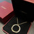 An image of a Cartier women's Tri Color Trinity Panthere Pendant necklace with diamonds, displayed at a slight angle, with the pendant closer to the bottom of the frame. The necklace features a gold, rose and white chain and a circular pendant, part of which is encrusted with diamonds, resting on a black interior of a red Cartier box with the brand name embossed in gold on the inside of the lid. The box is positioned on a brown surface, partially open, and the view is from a close distance, capturing the fine details of the necklace and the luxurious presentation. Comes in a great preowned condition.