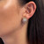 An image of a Rachel Koen diamond earring on a woman's left ear, viewed from a close, side angle. The earring features a starburst design with multiple diamonds, creating a sparkling effect against the earlobe. The photo is taken in clear, natural light to accentuate the earring's shine and intricate details. The earrings are pre-owned in a great condition. 