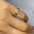An image of a Gucci ring for women, positioned on a finger at a slight angle to show the band's detail. The ring is a simple band without stones, featuring the Gucci GG logo and decorative patterns. It is in close-up view with a soft-focus background, emphasizing the ring's design.The ring is pre owned in a great condition. 