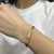 An image of a woman's wrist wearing a Rachel Koen bracelet adorned with diamonds. The bracelet is positioned horizontally across the wrist, showcasing its elegant design with a prominent diamond centerpiece. The photo is taken from a close angle, highlighting the intricate details of the jewelry against a neutral background.Excellent pre-owned condition. 