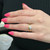 An image of a woman's hand wearing an engagement ring with diamonds. The ring is on the ring finger, positioned in the center of the image. The hand is angled slightly to the side, showing the ring from a close-up perspective. The diamonds are prominently visible, and the hand is adorned with pink nail polish, set against a dark background.Excellent pre-owned condition. 