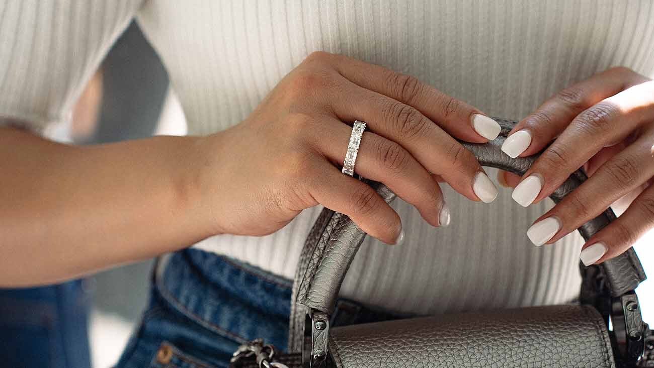 An Image of A Female's Hand Displaying Various Gold Bracelets with Diamonds. 