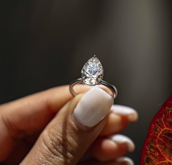 An image of a rose gold ring with diamonds sitting aside a white gold diamond ring seting atop a gray backdrop