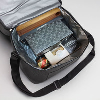 A cooler bag in grey containing a cheese kit, crackers, a jar, and a wooden board. It has a logo inside.