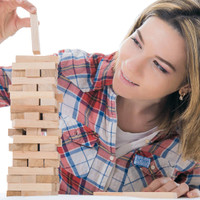 A woman stacking wooden blocks in a game of Tumbling Tower, featuring light-coloured natural wood blocks.