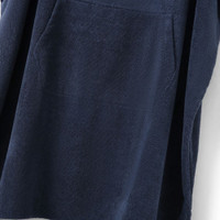 Navy blue terry cloth robe with pockets hanging on a white wall.