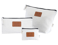 A set of three white fabric bags with black zippers and a branded leather patch.