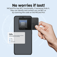A hand holds a black tracking tag next to a smartphone, featuring a QR code and a card with contact information.