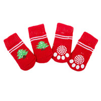 Four red pet socks displaying white paw prints and a green tree design. Each sock has a knitted texture and striped accents.