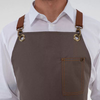 A grey apron with brown leather straps and multiple pockets, featuring a logo.