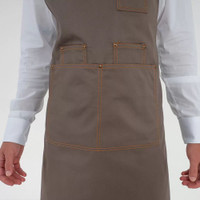 A grey apron with brown leather straps and multiple pockets, featuring a logo.