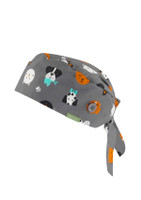 A unisex printed scrub cap in grey featuring various cartoon dogs in multiple colours and a button detail.