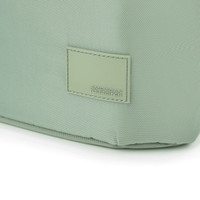 A green tote bag with a textured surface and a branded tag. The bag has a structured shape and sturdy construction.