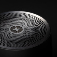 A black bass speaker featuring a perforated top surface and a logo.