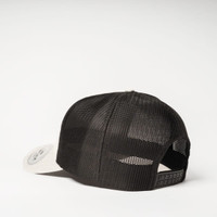 A trucker cap in black with a mesh back and a light-coloured brim, featuring a logo on the side.