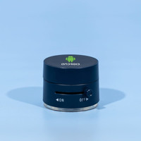 A black and silver device with a logo on top and a dial on the side, resting on a blue background.