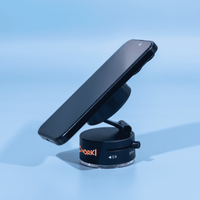 A black magnetic phone stand with a suction base, holding a smartphone at an angle against a light blue background.