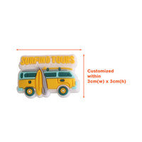 A yellow and green Clog Shoe Charm in the shape of a van with a surfboard and text above it.