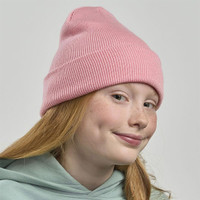 A pink ribbed beanie worn by a girl with red hair and freckles, featuring a logo on the side.