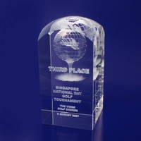 A crystal trophy with a dome top, featuring engraved text and a globe design, set against a blue background.