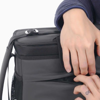 A black cooler bag with a hand reaching towards a zippered pocket, featuring a logo. Ideal for carrying drinks.