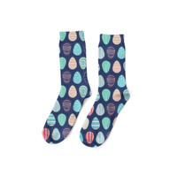 A pair of navy soccer socks featuring colourful, patterned circles in teal, peach, and pink. Includes a logo.