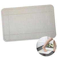 A textured rectangular bath mat in a light grey colour with a bordered design and a circular inset of a foot stepping on it.