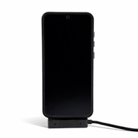 A black phone is displayed on a charger, connected by a charging cable. The charger has a sleek design.