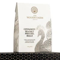 A bag of 100g cinnamon sea salt pretzel balls in a white and gold design, featuring a peacock motif.