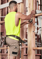 A man wearing khaki cargo shorts and a bright yellow sleeveless top, working with tools on a construction site.