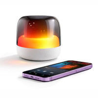 A Dazzle RGB Speaker in white with a glowing gradient light beside a smartphone displaying music controls.