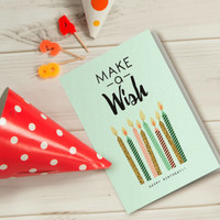 A light green gift card featuring birthday candles, surrounded by a red polka dot party hat and colourful candle numbers.