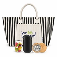 A striped tote bag in black and white with a cream pocket, a jar of colourful sweets, a black drink container, and a wooden item.