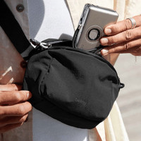 A black Bellroy Lite Belt Bag being held by a person, with a phone partially visible in an outer pocket.