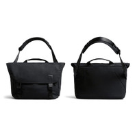 A black messenger bag with adjustable strap, featuring a flap closure and carry handles, along with a subtle logo.