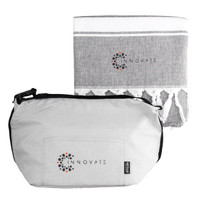 A grey cooler bag with a zipper and a matching grey towel featuring tassels. Both items have a logo.