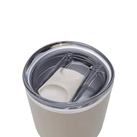 A drink bottle with a stainless steel body and a clear, sealed lid, featuring a logo. Primarily in light beige colour.