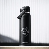 A drink bottle in matte black with a flip straw lid and a logo featuring a vanlife theme.
