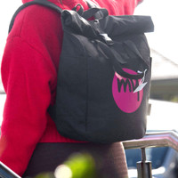 A black recycled canvas backpack tote featuring a logo, carried on a person’s back.