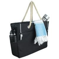 A black waterproof beach bag with a rope handle, featuring a drink bottle, a towel, and side pockets.