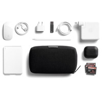 A black tech kit surrounded by a white power bank, mouse, charging cables, a stylus, AirPods, and a USB drive.