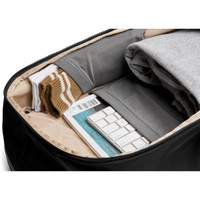 A sleek black backpack interior with neatly folded clothing, socks, and a keyboard in organised compartments.