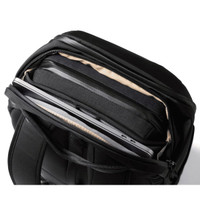 A black backpack with a zippered compartment showcasing a laptop and padded interior. It features a logo.