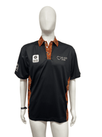 A black short sleeve polo shirt with patterned orange accents and a logo on the chest. It features a collar and is displayed on a mannequin.