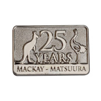 A metallic lapel pin featuring a kangaroo and an emu, with the text "25 YEARS MACKAY - MATSUURA."