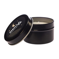 A black tin candle with an open lid, featuring a decorative label that includes stars and a crescent moon design.